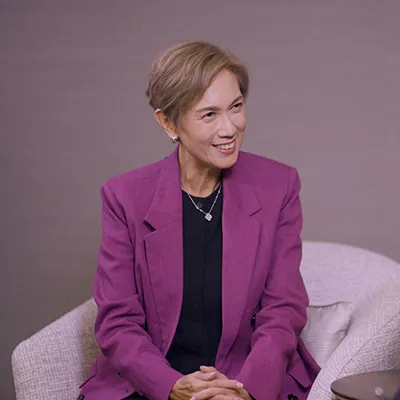 Woman in a purple blazer smiling during an interview, with a McKinsey & Company logo in the background.