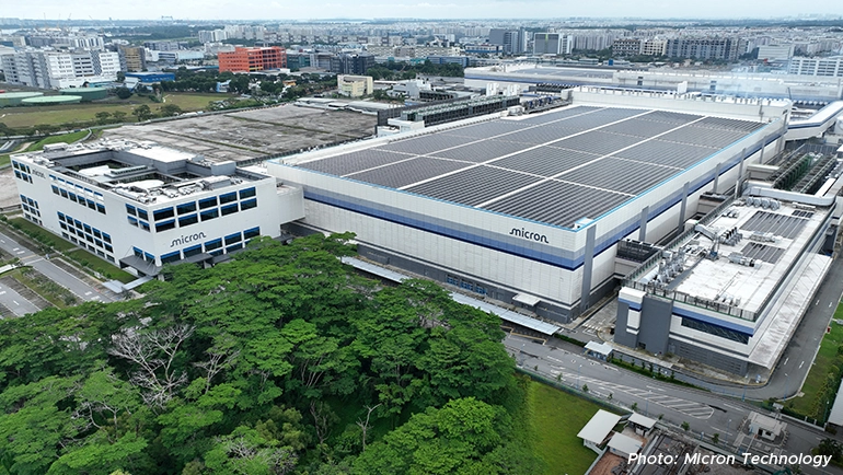 Aerial view of Micron Technology’s large-scale manufacturing facility with rooftop solar panels, surrounded by greenery and industrial infrastructure.