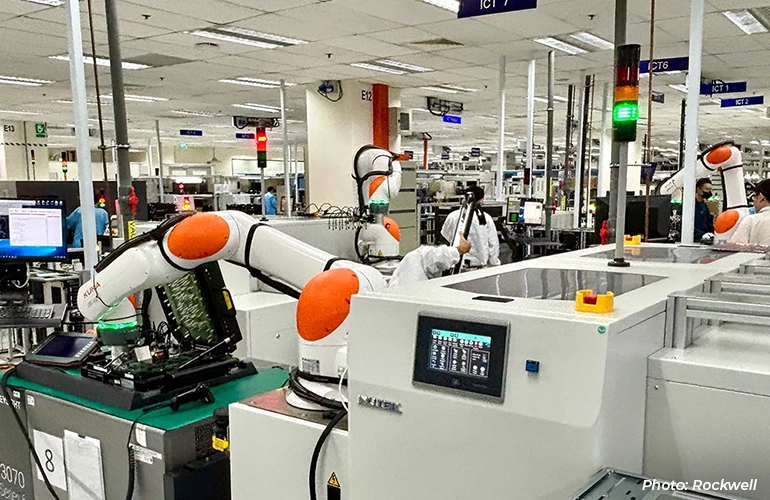 Robotic arms operating automated equipment inside a manufacturing facility.