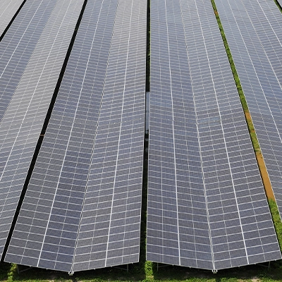 Aerial view of floating solar panels on a body of water beside a dense green forest.