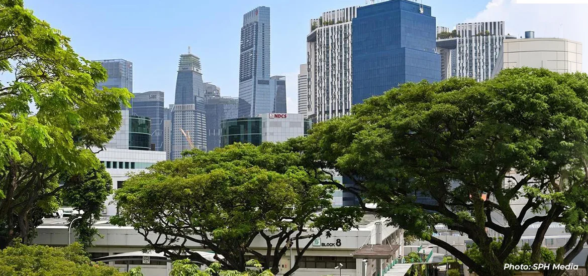 Singapore city skyline seen above lush greenery and low-rise buildings.