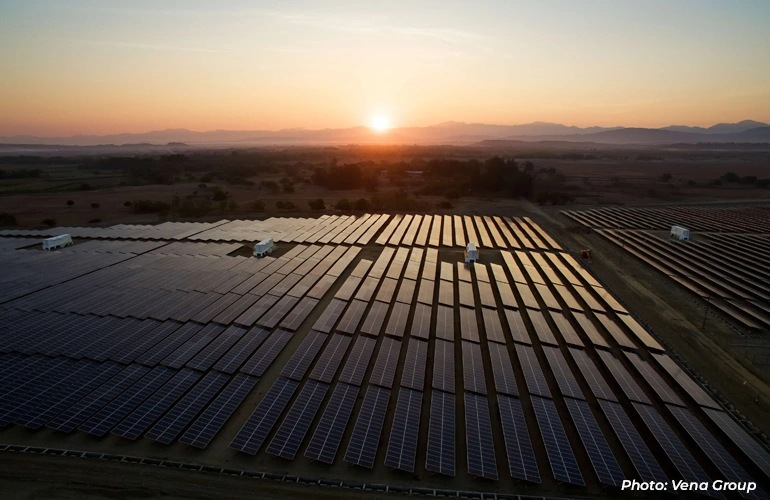 Solar panel farm at sunset with rows of panels stretching across the landscape.