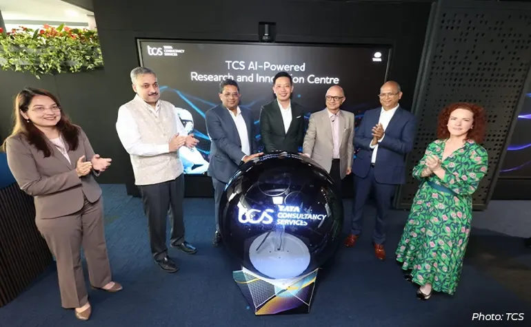 Group of executives and partners at the launch of the TCS AI-Powered Research and Innovation Centre, standing around a ceremonial digital globe display inside a modern TCS event space.