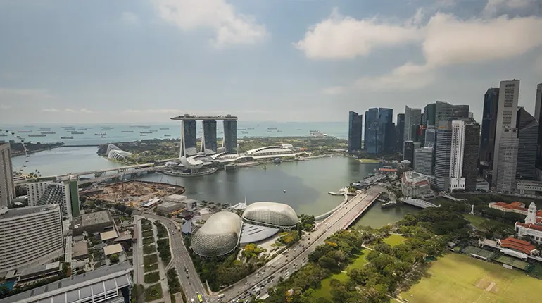 Aerial view of Singapore’s Marina Bay area featuring Marina Bay Sands, the Esplanade, and the surrounding city skyline by the waterfront.