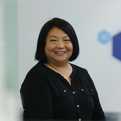 Woman smiling in an office setting, with abstract technology and innovation icons displayed on the wall in the background.