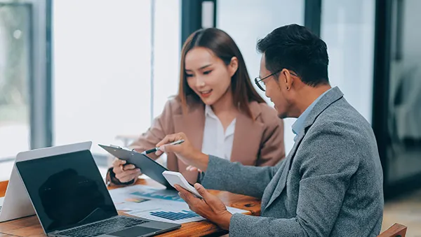 Two business professionals discussing documents and data at a desk with laptops, symbolizing dedicated support and a business-friendly environment.