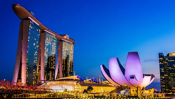 Night view of Marina Bay Sands and the ArtScience Museum in Singapore, illuminated against the evening sky, representing Singapore’s vibrant and business-friendly environment.
