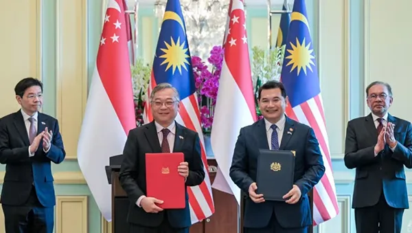 Singaporean and Malaysian officials holding signed agreements in front of their national flags, symbolizing a landmark bilateral partnership and shared vision for growth.