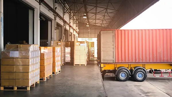 Shipping container at a warehouse loading dock with stacked pallets, symbolizing supply chain resilience and efficient logistics operations.