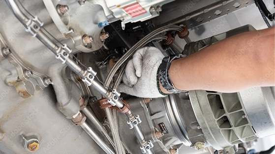 Technician’s gloved hand working on aircraft engine components, representing MRO and aftermarket services.