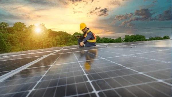 Worker installing solar panels at sunset, symbolizing efforts to build a sustainable green ecosystem.