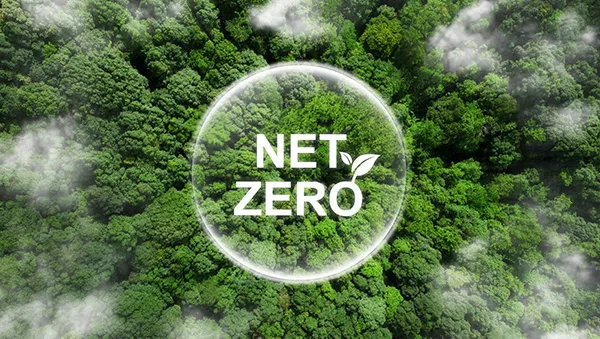 Aerial view of lush green forest with "NET ZERO" text overlay, symbolizing sustainability leadership and commitment to carbon neutrality in advanced manufacturing.