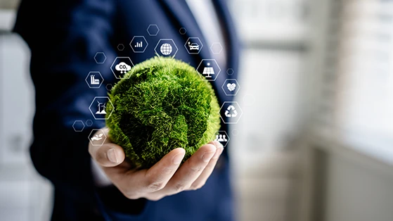 Person in a suit holding a green moss-covered globe with digital sustainability and carbon-related icons floating around it.