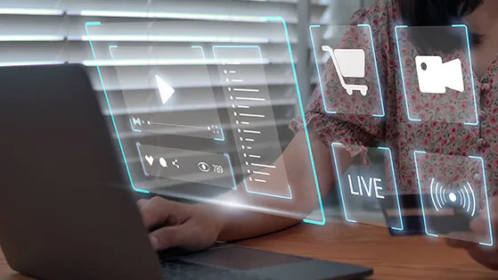 Person using a laptop with holographic digital interface icons showing video playback, live streaming, shopping cart, and social engagement, representing AI-driven e-commerce and digital media technologies.