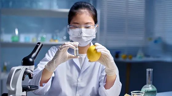 Scientist wearing protective gear inspecting leafy greens grown indoors under LED lights in a controlled environment, showcasing agricultural innovation and food technology for health and wellness.