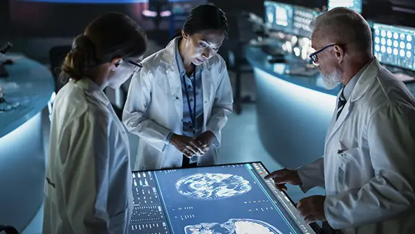 Doctors analyzing brain scans on a large digital touchscreen.