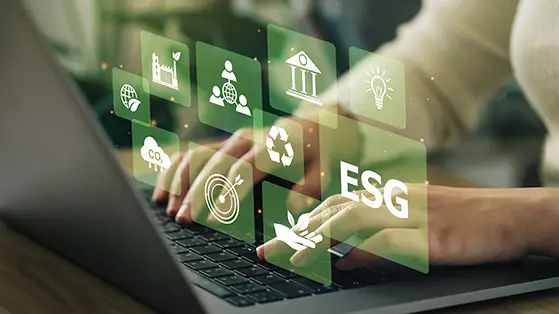 Hands typing on a laptop with floating green ESG icons, symbolizing digital tools for sustainability and decarbonisation efforts.