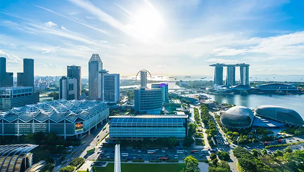 Aerial view of Singapore’s Marina Bay area with the skyline, Marina Bay Sands, the Singapore Flyer, and the Esplanade under a bright blue sky.