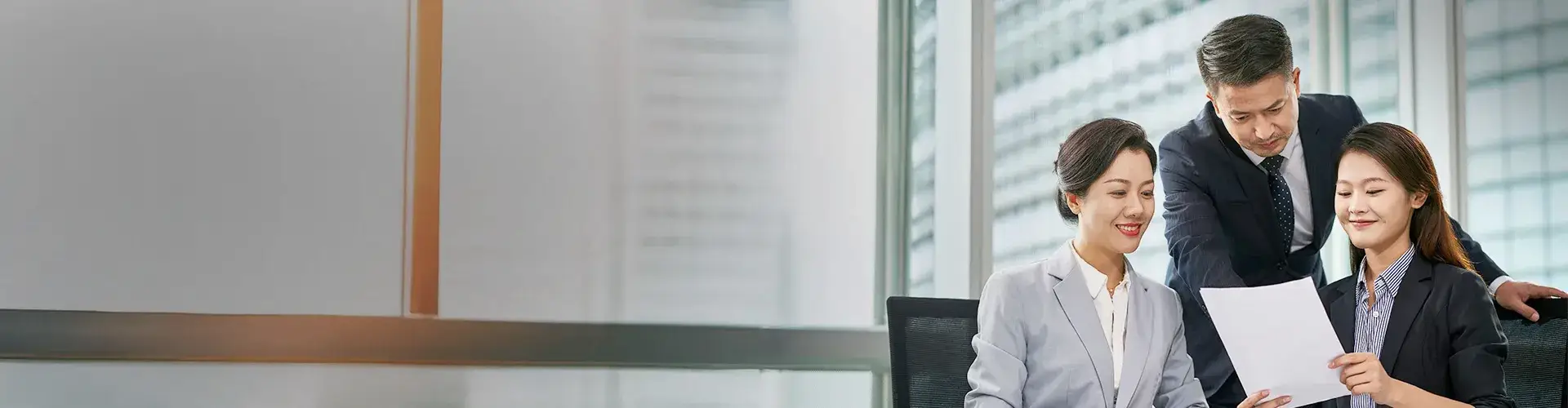 Three business professionals discussing documents in a bright, modern office, representing strategic planning and professional collaboration.