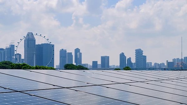 Solar panels in the foreground with Singapore’s city skyline and the Singapore Flyer in the background, illustrating the city’s commitment to renewable energy and sustainability.