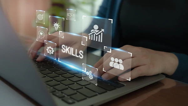 Close-up of hands typing on a laptop keyboard with digital icons representing various workforce skills and qualifications, including data analysis, teamwork, and innovation.