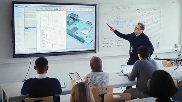 Instructor presenting circuit board designs to students, representing collaboration between industry and academia.