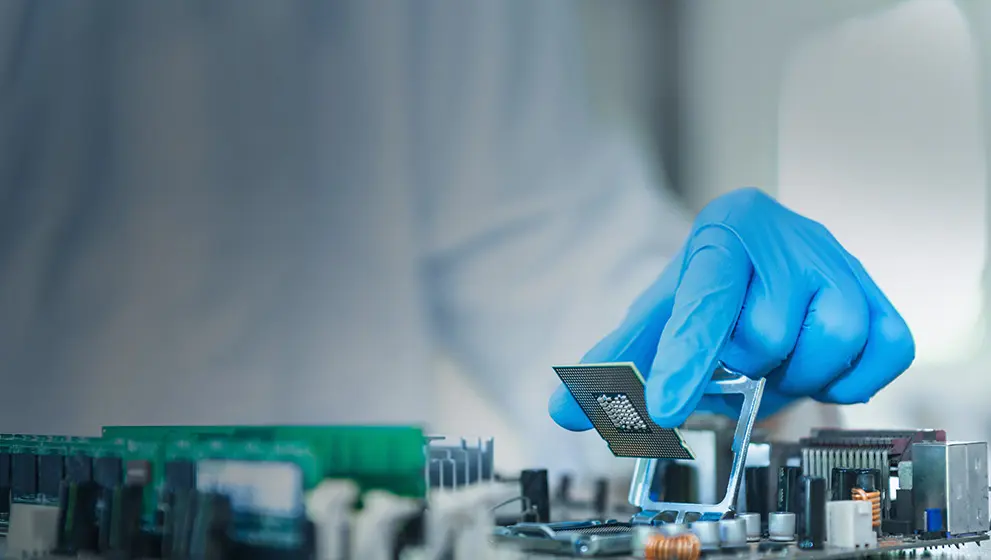 Gloved hand installing a microchip onto a circuit board, symbolizing advanced semiconductor technology and precision engineering.