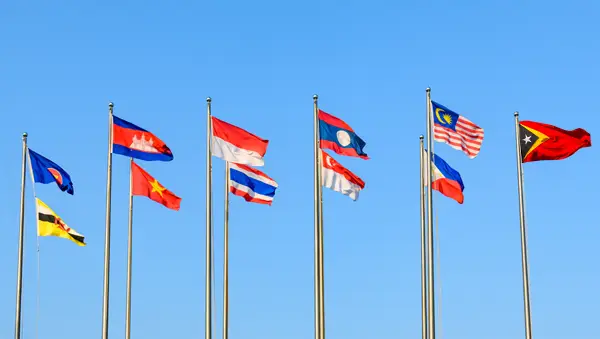 Flags of Southeast Asian nations representing the ASEAN bloc against a clear blue sky, symbolizing regional unity and strategic market opportunities in Southeast Asia.