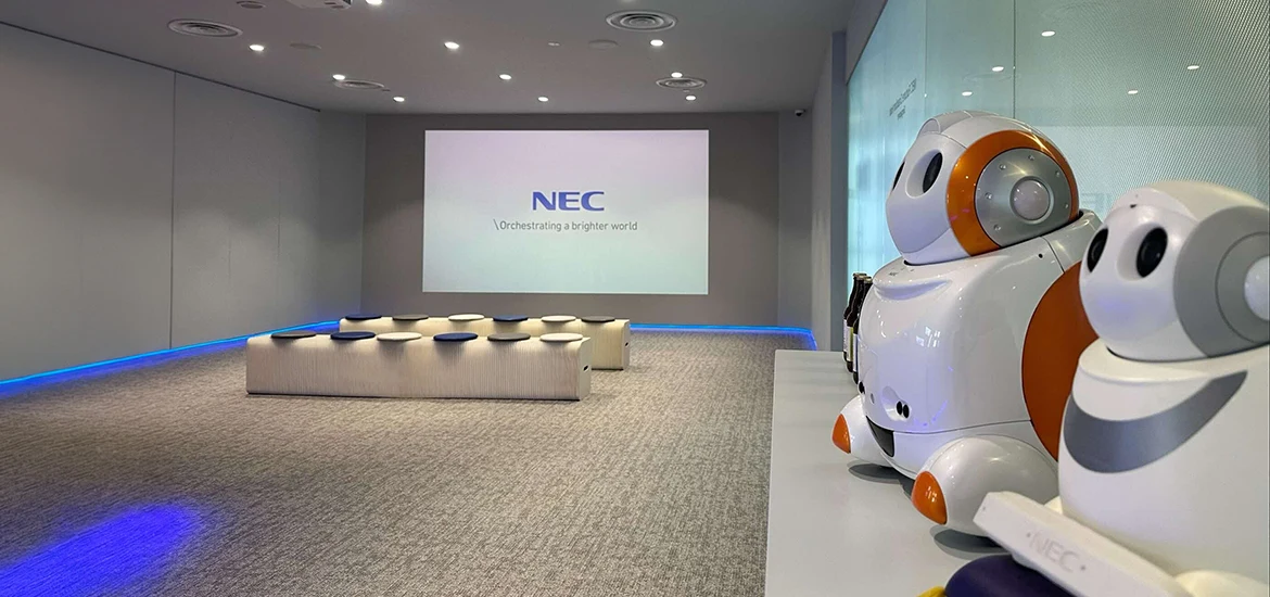 NEC presentation room with robot displays and a projected screen.
