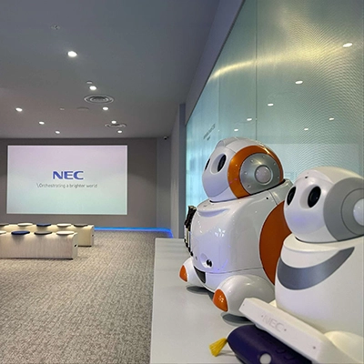 NEC presentation room with robot displays and a projected screen.