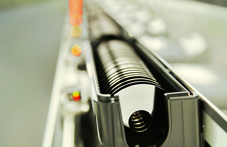 Close-up view of precision-engineered cylindrical components aligned on an automated production line, highlighting advanced manufacturing processes and high-precision industrial fabrication.