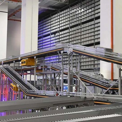 A high-tech automated warehouse featuring an intricate system of conveyor belts and robotic tracks, designed for efficient sorting and transportation of goods. The background includes towering storage racks filled with uniform bins, illuminated with blue and red accent lighting.