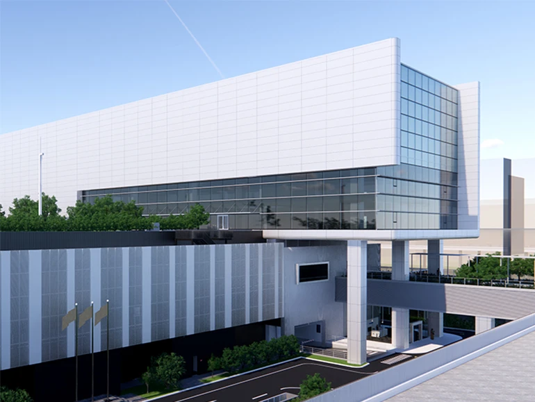 Modern industrial or tech facility with sleek architecture, large glass windows, rooftop greenery, and a connecting elevated walkway.