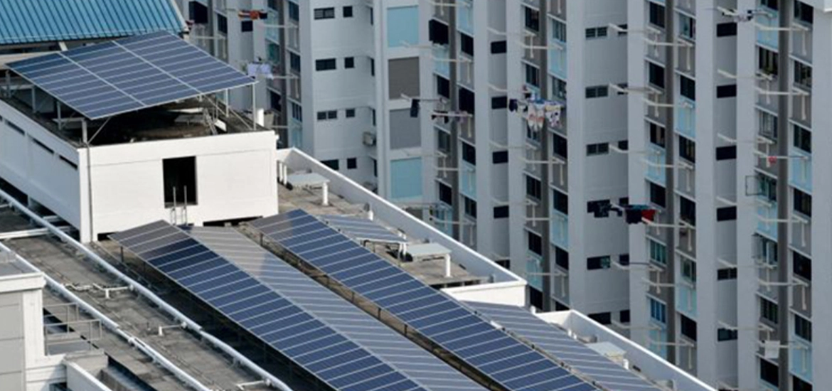 Rooftop solar panels installed on high-rise residential buildings, with laundry hanging from balconies in the background.