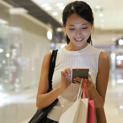 A lady checking on her phone while smiling in the mall.
