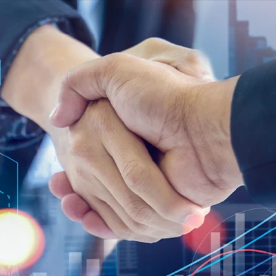 Close-up of two people shaking hands, symbolizing a business agreement or partnership. In the background, there are abstract financial graphs and bar charts, suggesting economic or corporate success.