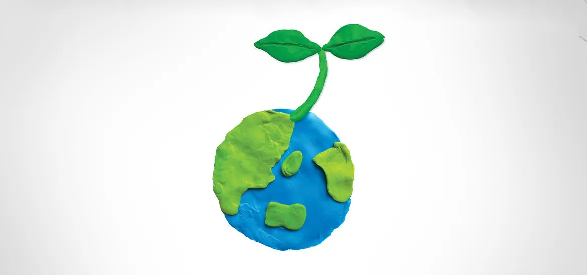 Clay model of Earth with a green sprout growing from it, symbolizing sustainability, environmental care, and a greener future.