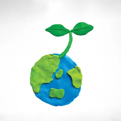 Clay model of Earth with a green sprout growing from it, symbolizing sustainability, environmental care, and a greener future.