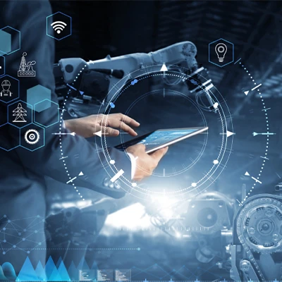 Person using a tablet to interact with robotic arms and futuristic digital interface icons in a smart manufacturing environment.