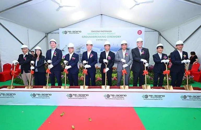 Groundbreaking ceremony for a new semiconductor manufacturing facility, featuring company executives and officials in hard hats holding ceremonial shovels on a stage during the project launch event.