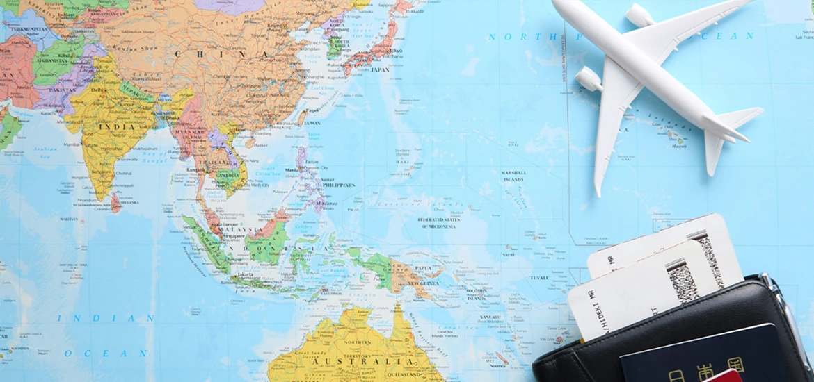 Travel items including a passport, boarding passes, and a toy airplane placed on a world map.