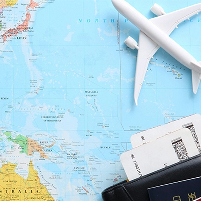Travel items including a passport, boarding passes, and a toy airplane placed on a world map.