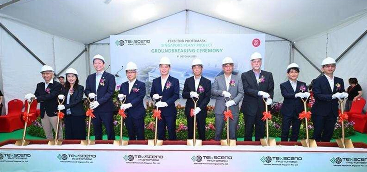 Group of executives in formal attire and safety helmets holding ceremonial shovels at the Tekscento Photomask Singapore project groundbreaking ceremony.