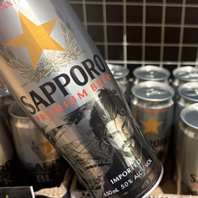 Close-up of a Sapporo Premium Beer can with more cans in the background.