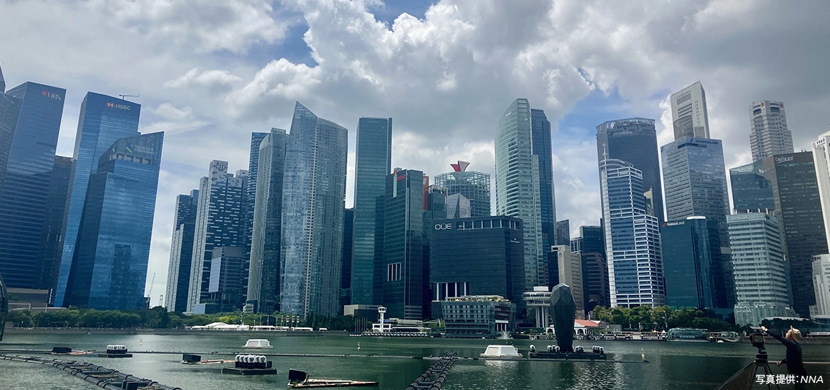 Singapore’s central business district skyline with modern skyscrapers along Marina Bay, reflected in the water under a cloudy sky.