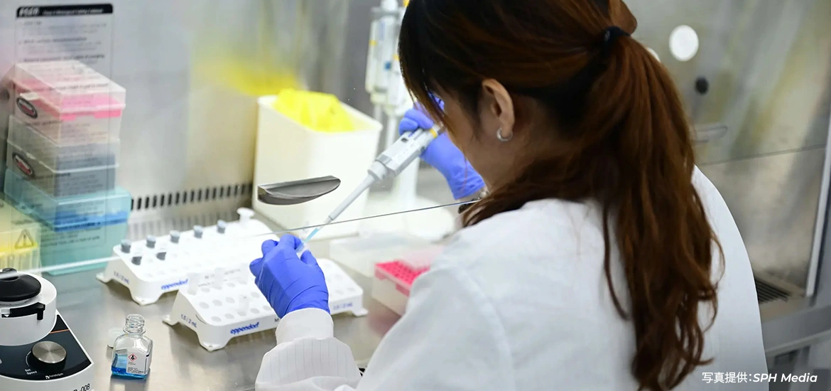 Researcher using a pipette to conduct laboratory work inside a biosafety cabinet.