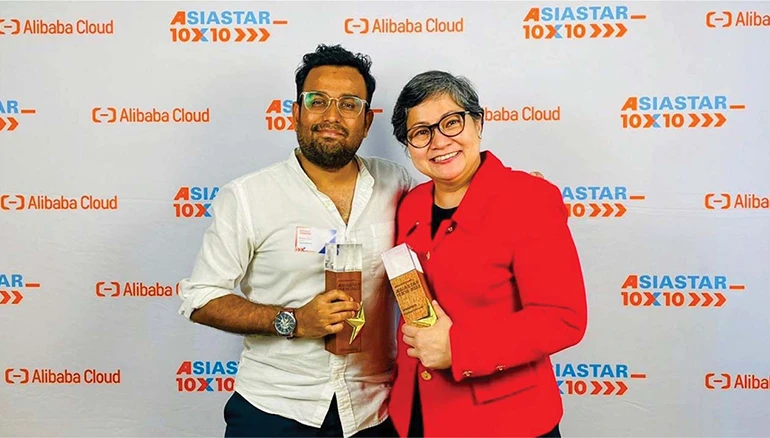 Two award recipients smiling with trophies at the AsiaStar 10x10 event, presented by Alibaba Cloud, celebrating innovation and excellence in the tech industry.