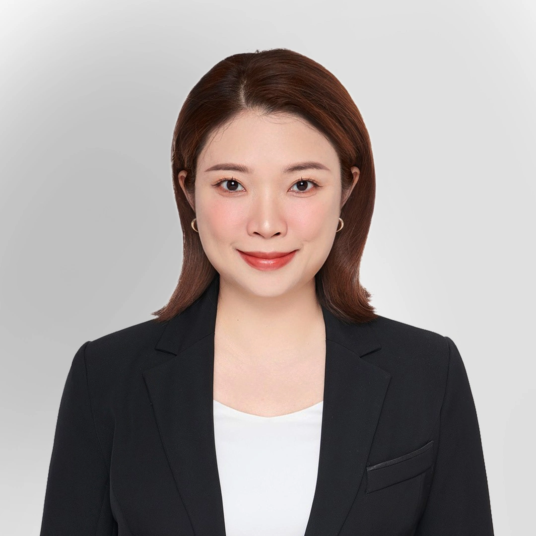 Portrait of a woman in a black blazer and white top smiling against a plain background.