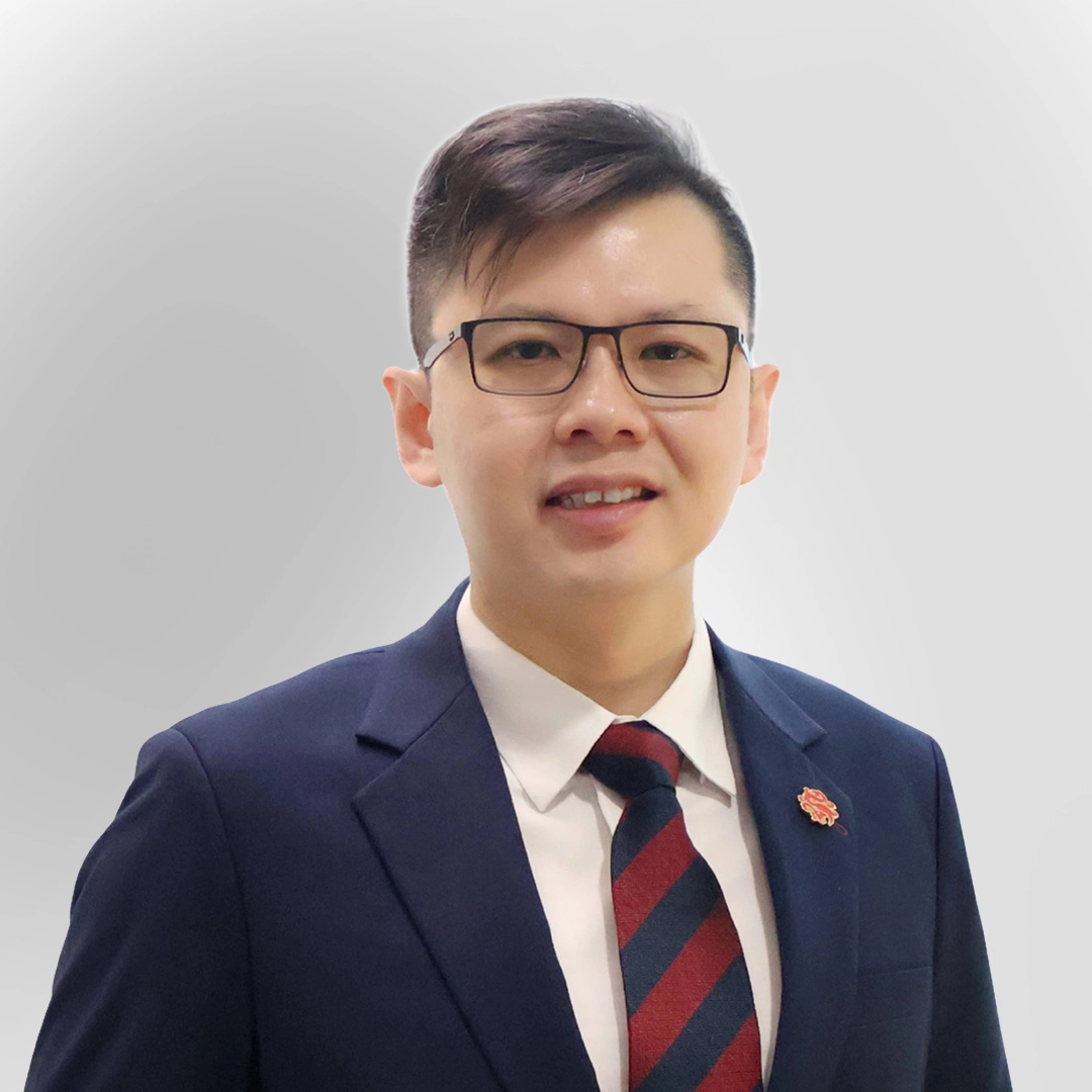 Portrait of a man wearing glasses, a suit, and a striped tie, smiling against a plain background.