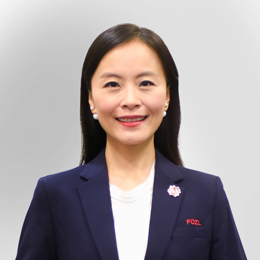 Portrait of a woman in a navy blazer and white top, smiling against a plain background.